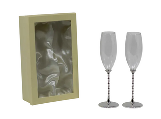 Two silver champagne flutes in front of a beige box with a reflective interior.