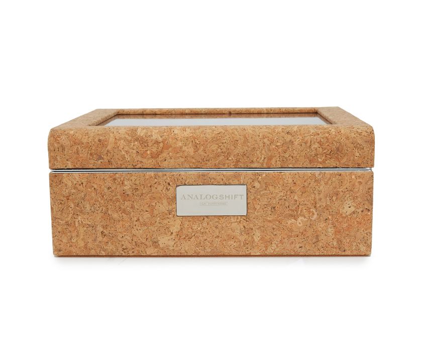 An 8 piece cork watch box with a dark tan Ultrasuede lining and a display window, featuring a branded label on the front.