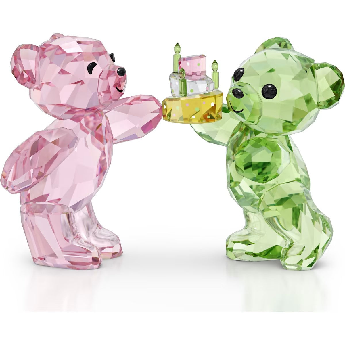 Two crystal bear figurines, one pink and one green, holding a cake on a white background.