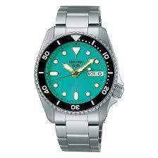 A Seiko 5 Sports watch with a green dial, silver metallic band, and case.