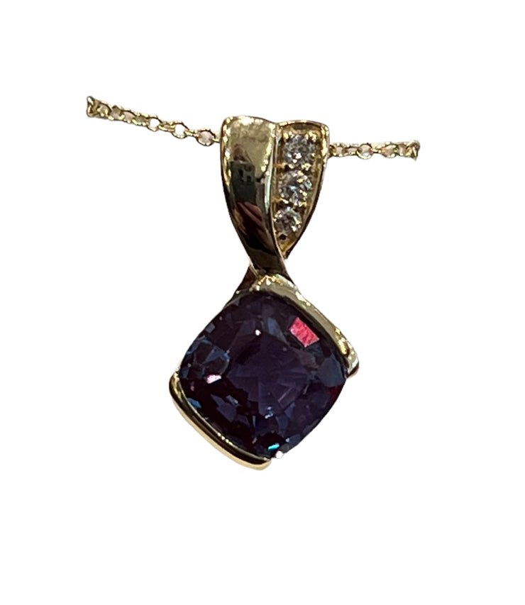 Gold pendant with a dark purple gemstone on a white background