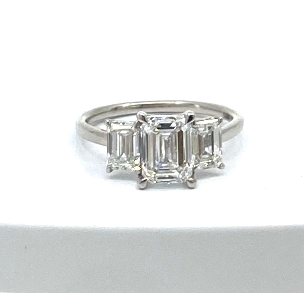 Diamond ring with emerald-cut stones on a white background