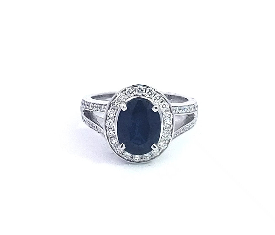 A 14K white gold sapphire and diamond ring with a round cut sapphire centerpiece and smaller round cut diamonds set in a classic six-prong setting.