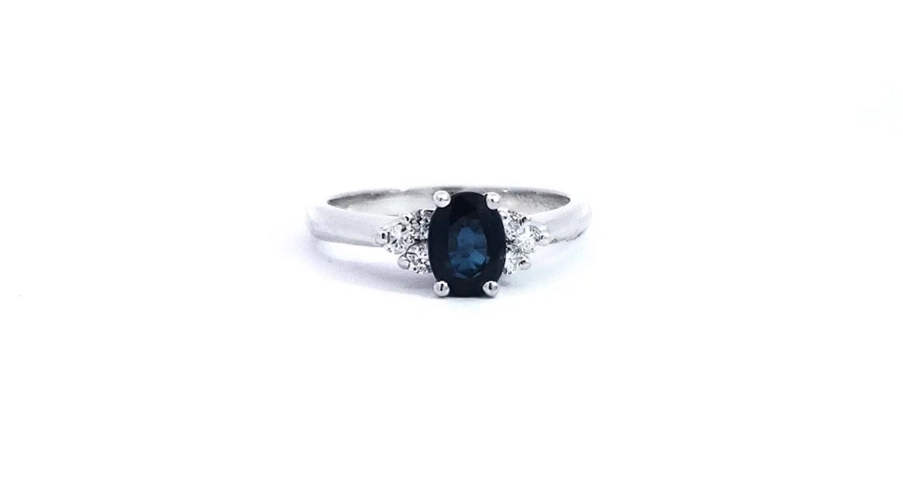 A 14K white gold sapphire and diamond ring with a size 6. The ring has a central sapphire stone surrounded by two smaller diamonds.