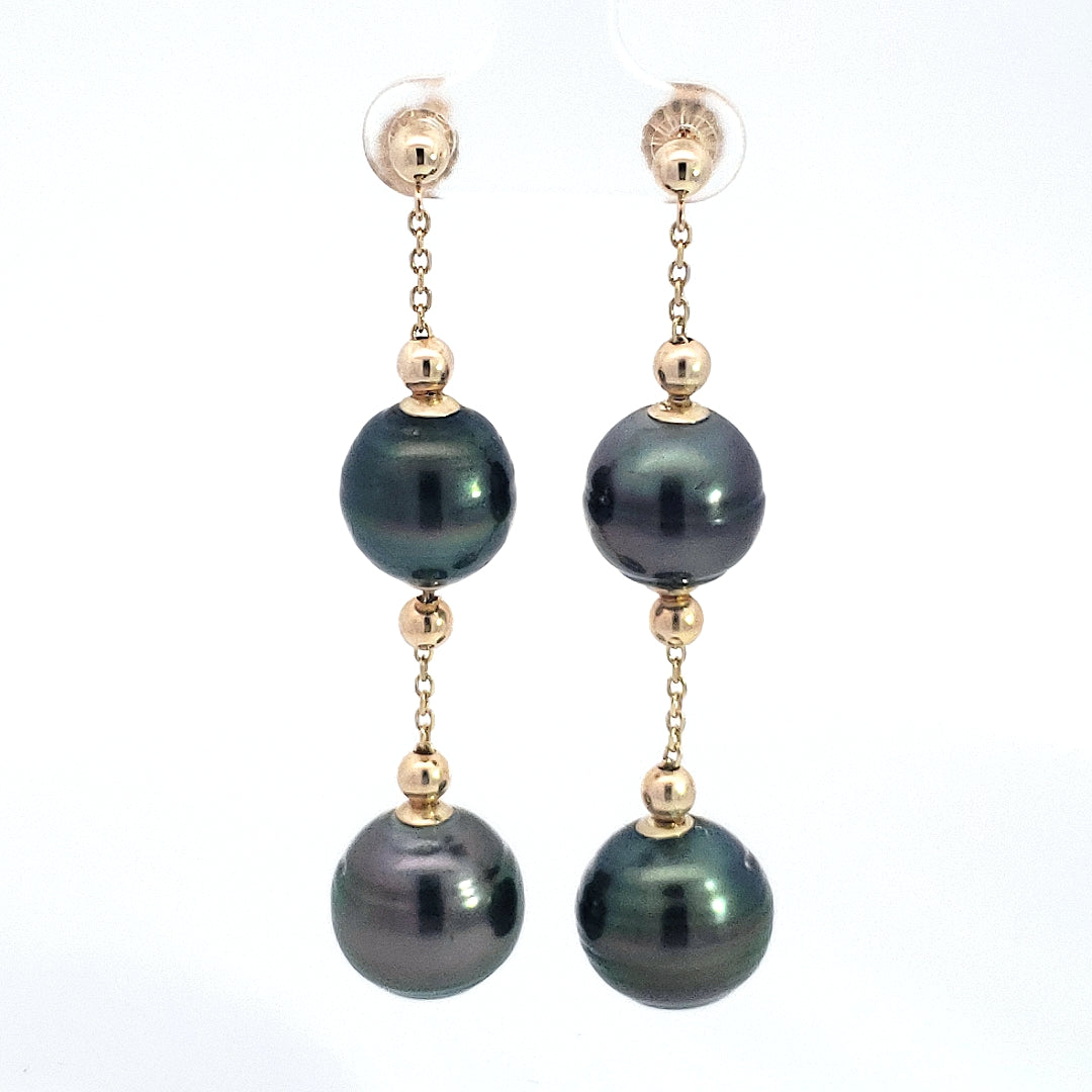 Pair of earrings with dark pearls and gold accents on a white background