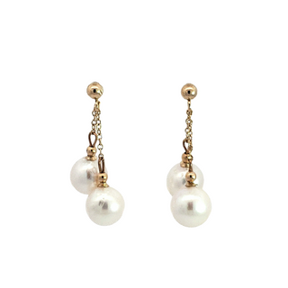 Pair of pearl earrings with gold chains on a white background