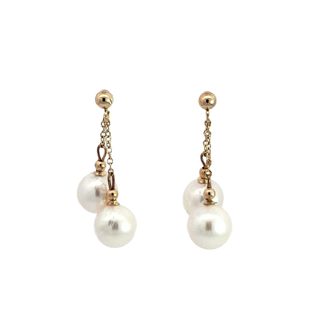 Pair of pearl earrings with gold chains on a white background