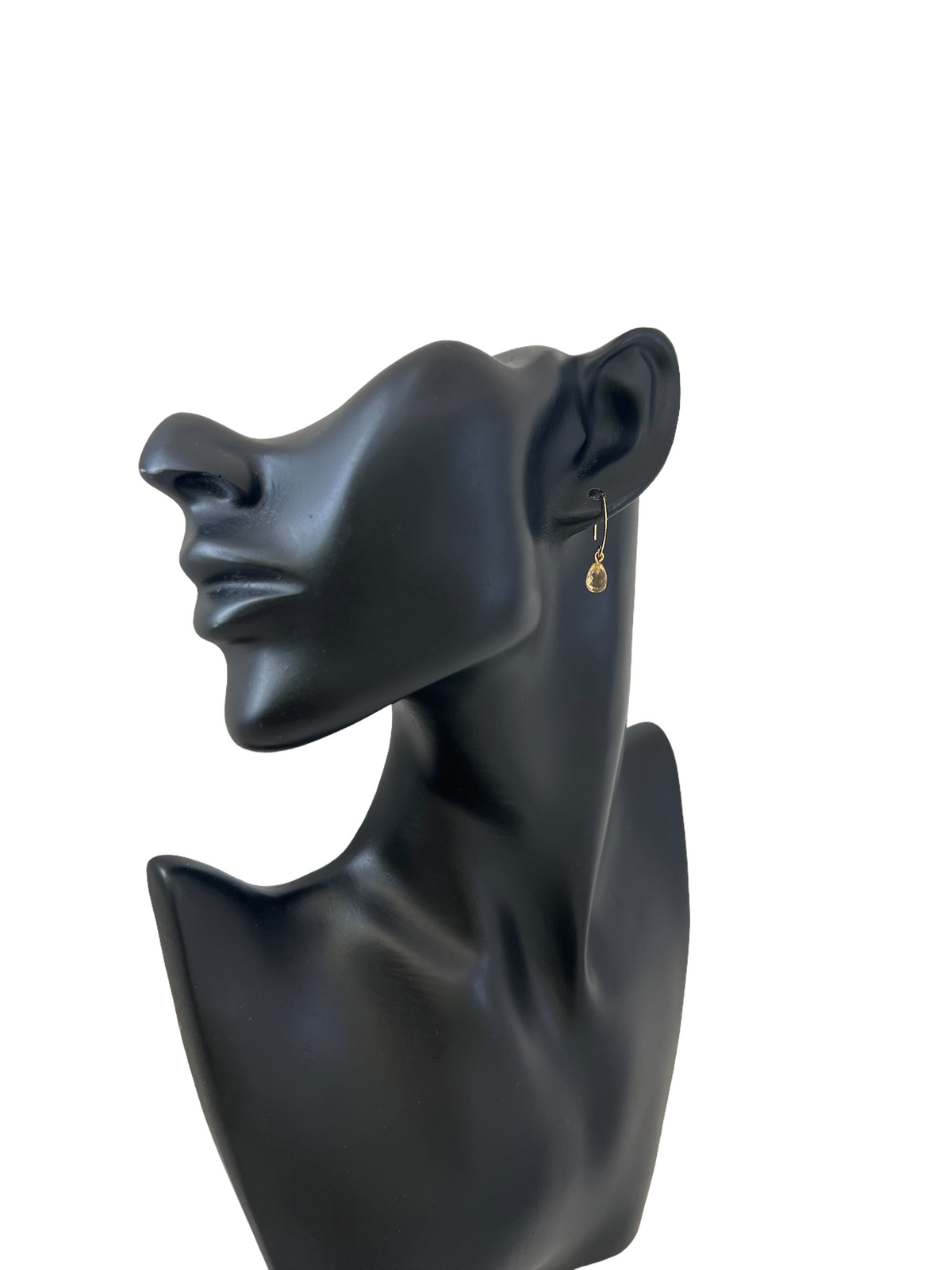 Black sculpture of a face with an earring on a white background