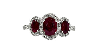 Ring with three red gemstones and diamond accents on a white background
