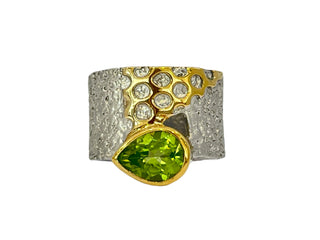 Jewelry ring with green gemstone and gold accents on a white background