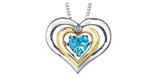 Heart-shaped pendant with blue gemstone and gold and silver accents on a white background